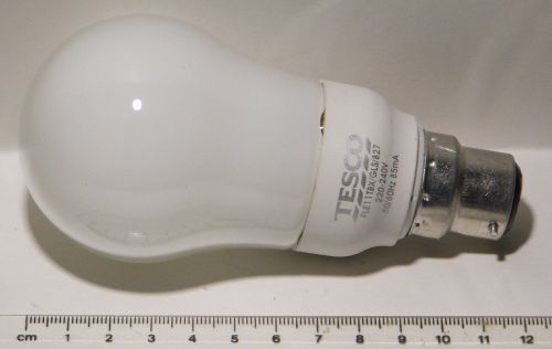 Tesco FLE11TBX-XM-GLS-827-B22-TESCO/1 Compact Fluorescent Lamp - Displayed with a ruler to show lamp size