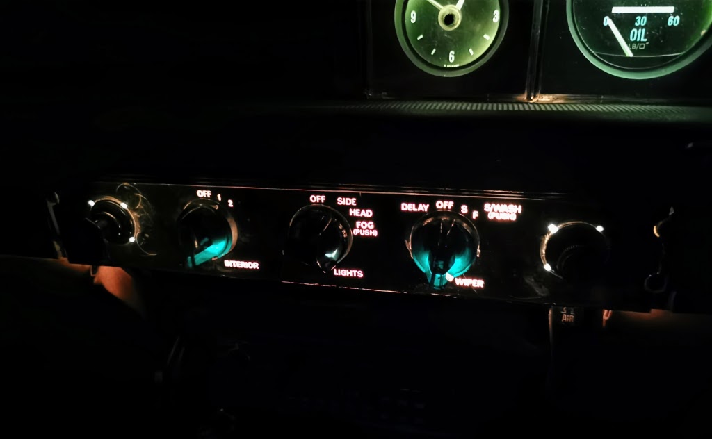 Detail of the central dash switchgear on a 1975 Rover P6B shown when illuminated