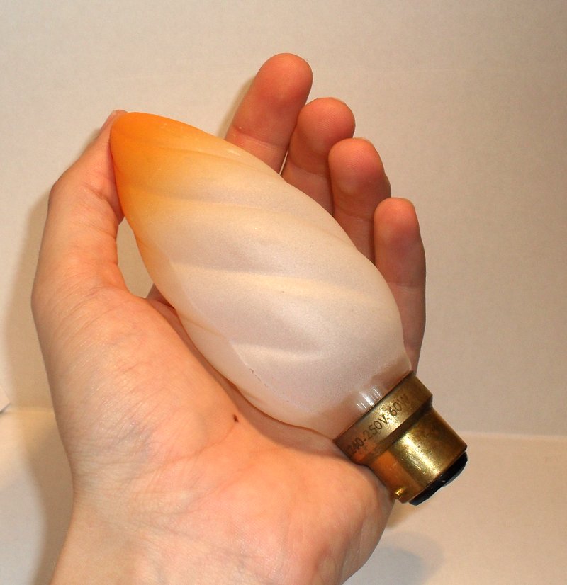BELL 60W Twisted Candle Lamp with Amber Tip - Shown held in hand for scale