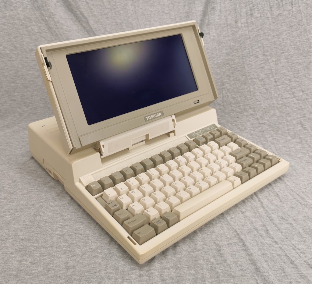 General overview of a Toshiba T1200 from the left with the display open